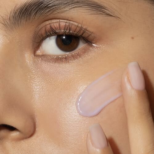 Close-up of a person applying skincare cream to the cheek.